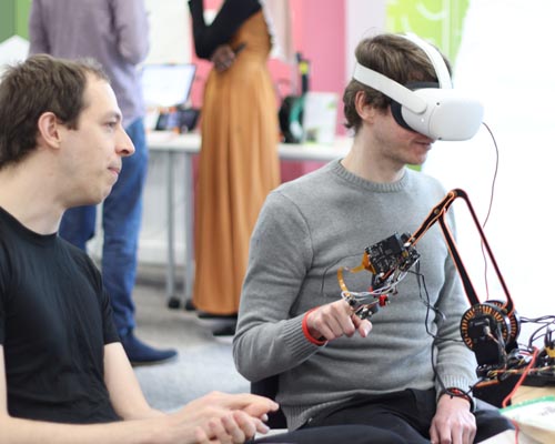 news_launch_01 Photo of someone demonstrating a digital device while wearing a VR headset at the prosquared launch event