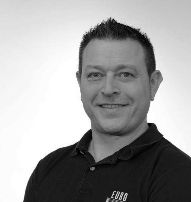 Steve-Jones A black and white photo of Steve Jones, smiling and facing the camera against a white background.