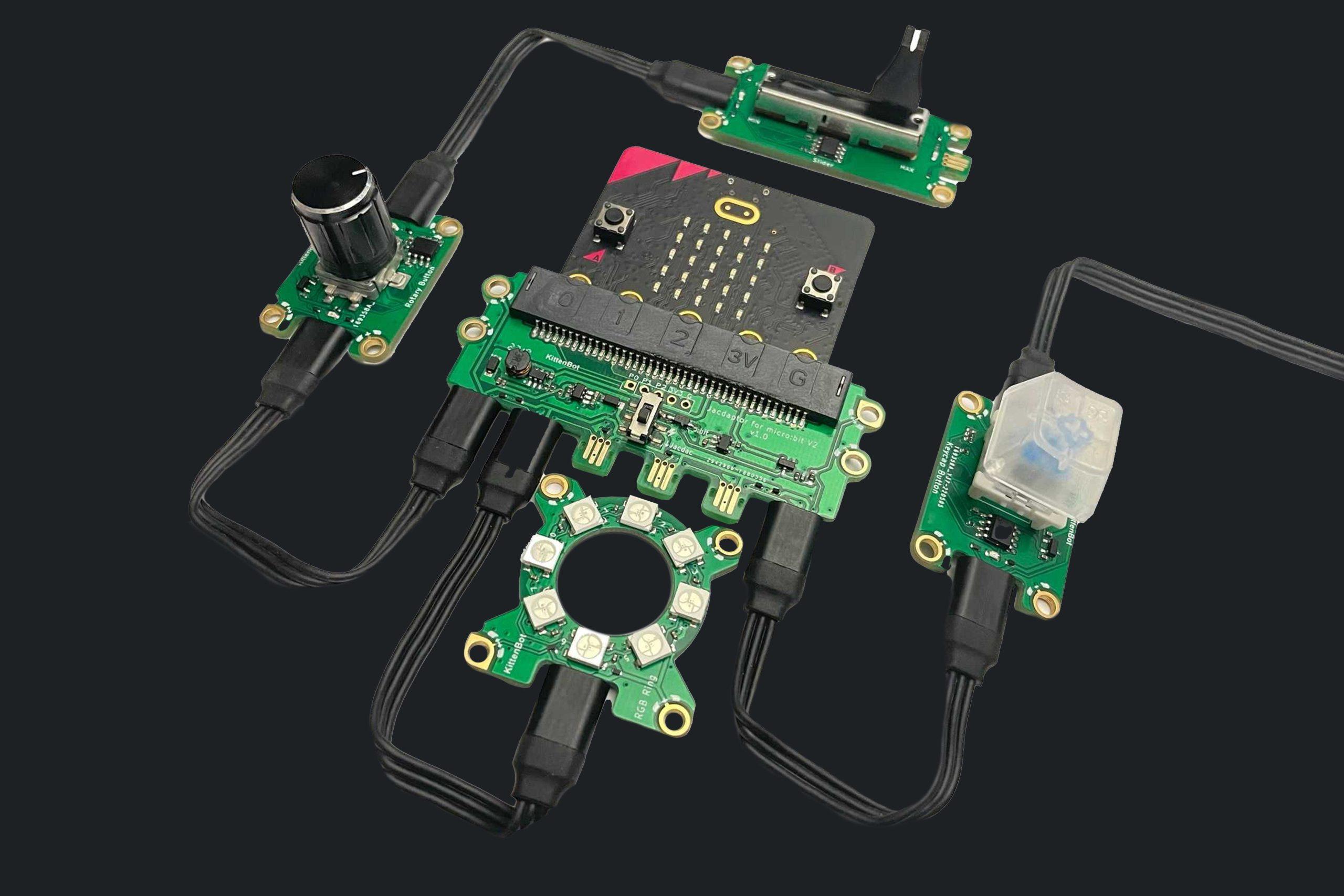 REPLICATE_landscape A photo of a micro:bit circuit board connected to a variety of Jacdac electronic components by black cables on a black background.