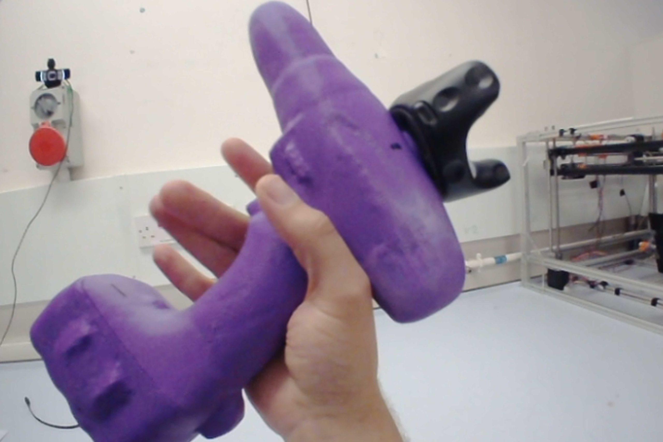 Multi-modal_04 A person's hand holding a purple device prototype with a lab in the background.
