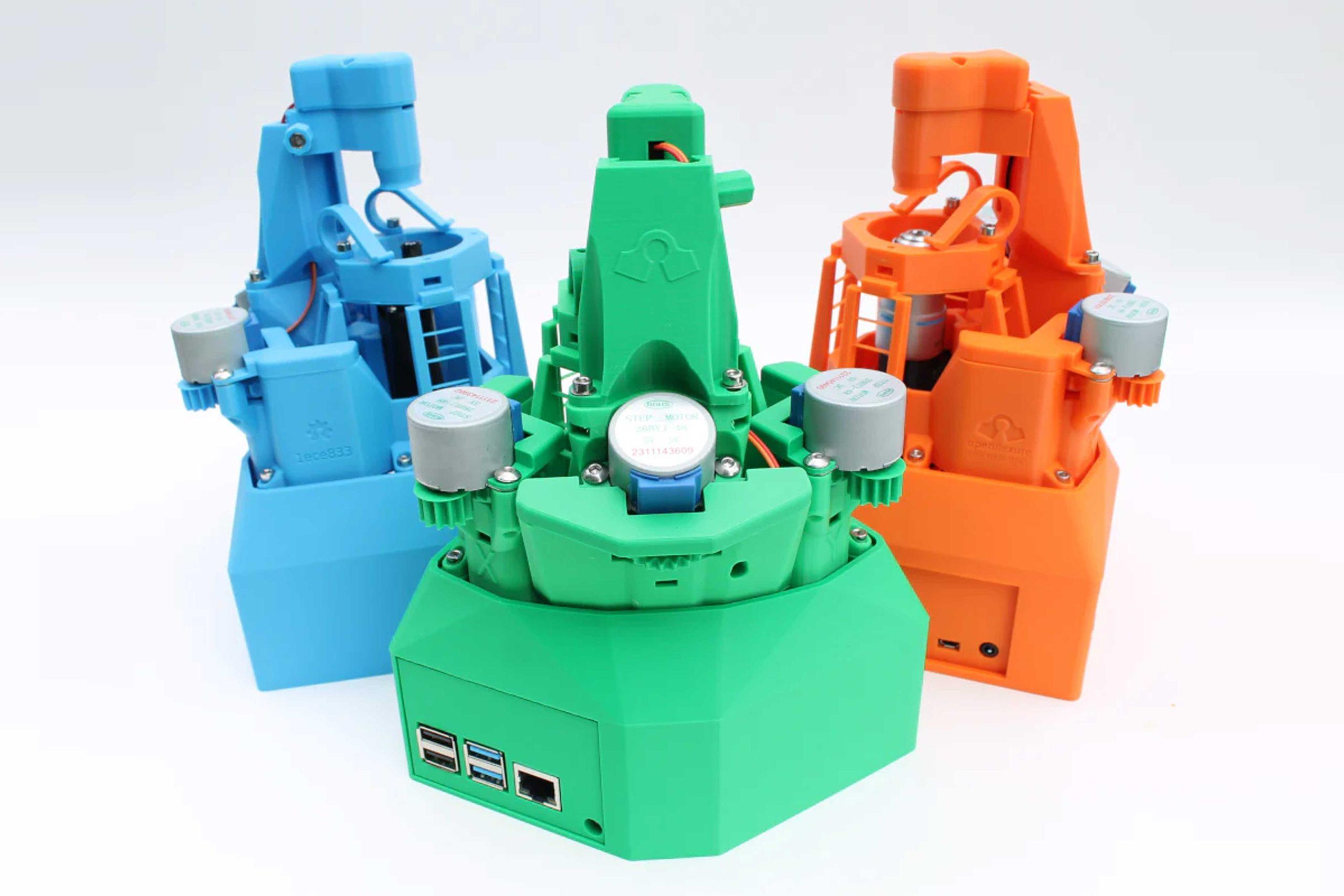 OpenFlexure_03 A photo of three OpenFlexure microscopes which have been 3D printed in bright colours against a white background.