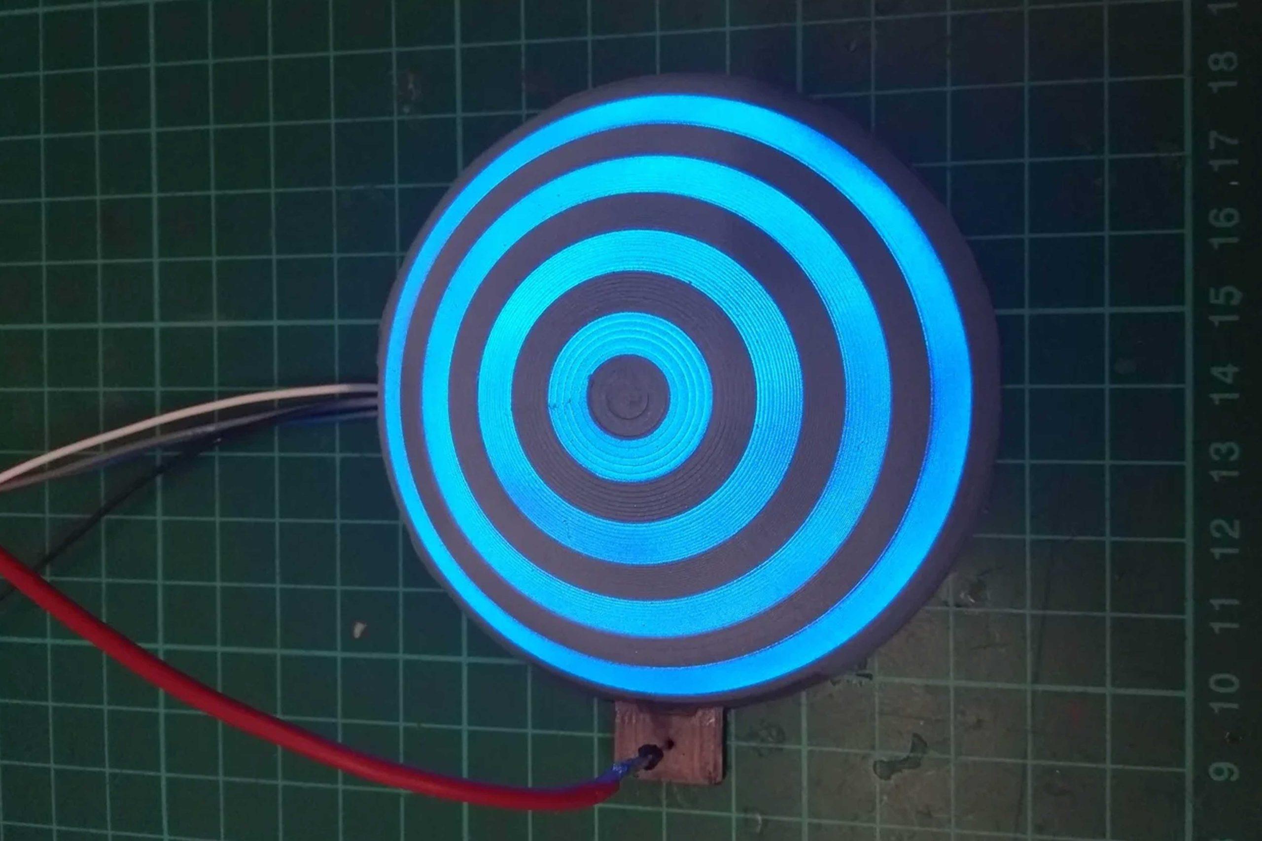 active_01 A disc painted with concentric circles of grey and glowing blue paint against a grid.