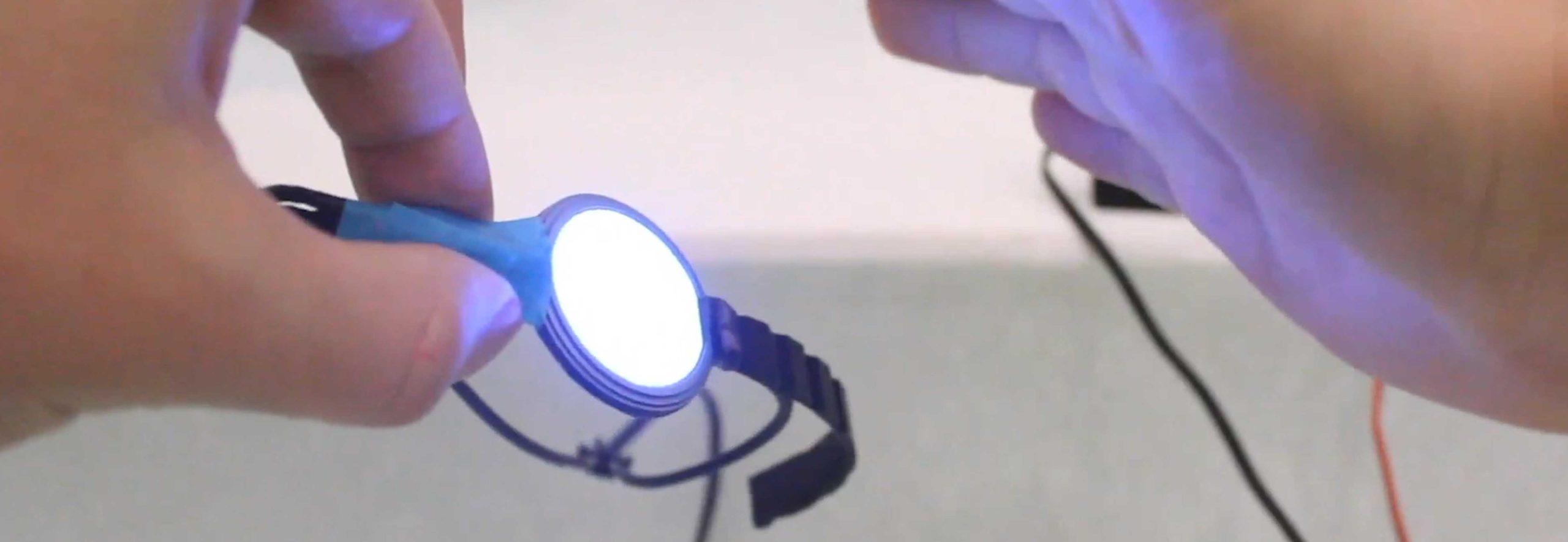 active_watch A person's hands holding a wearable electronic band, part of which is glowing white.