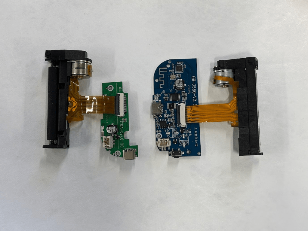 The parts of two electronic devices removed from their casings and laid out on a white surface.