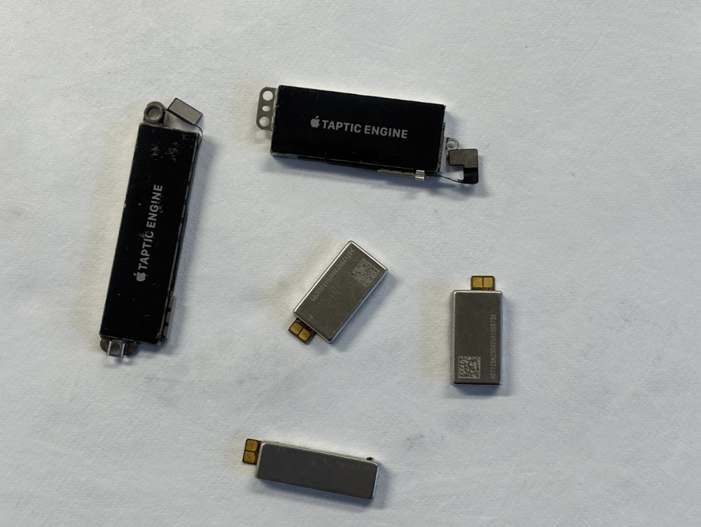 Five small electronic components called Linear Resonant Actuators lying on a white surface.