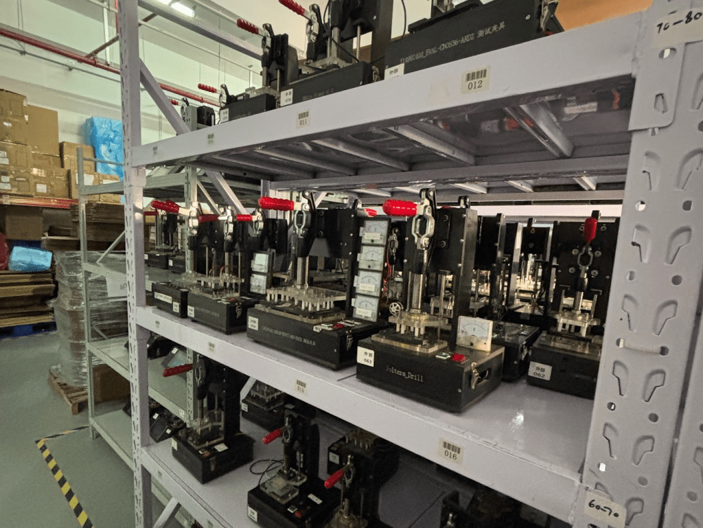 Machines for making electronics sit on shelves in a large warehouse.