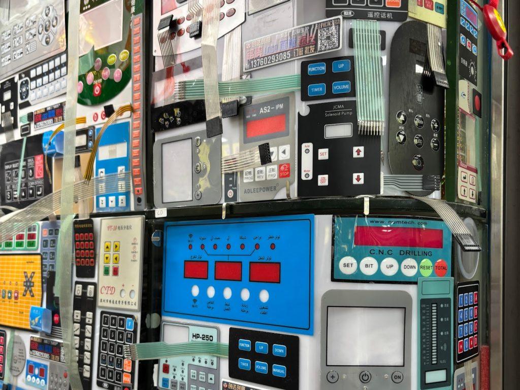 A wall is covered in membrane interfaces on display. They are brightly coloured with many buttons.
