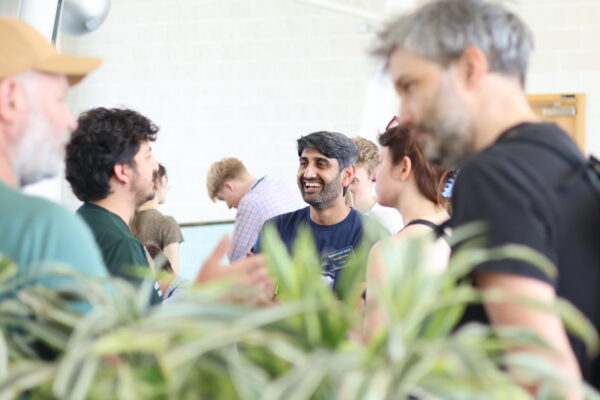 Summer school delegates network during a speed dating session, with indoor plants in the foreground.